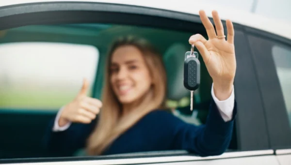 Autofahrerin hält Autoschlüssel hoch