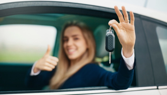 Autofahrerin hält Autoschlüssel hoch
